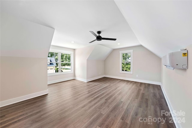 additional living space with vaulted ceiling, plenty of natural light, dark wood-type flooring, and ceiling fan