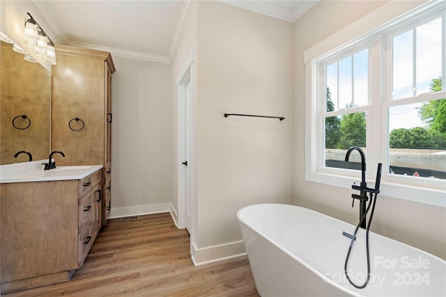 bathroom with a bathtub, wood-type flooring, crown molding, and vanity