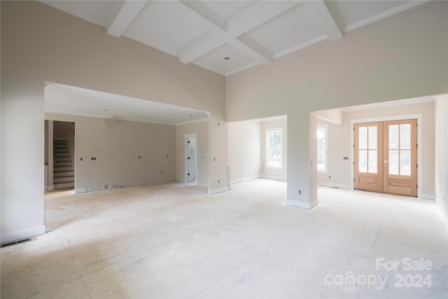 unfurnished living room featuring french doors, ornamental molding, coffered ceiling, beamed ceiling, and a high ceiling