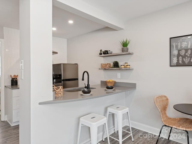 kitchen featuring hardwood / wood-style flooring, sink, stainless steel fridge, and beam ceiling