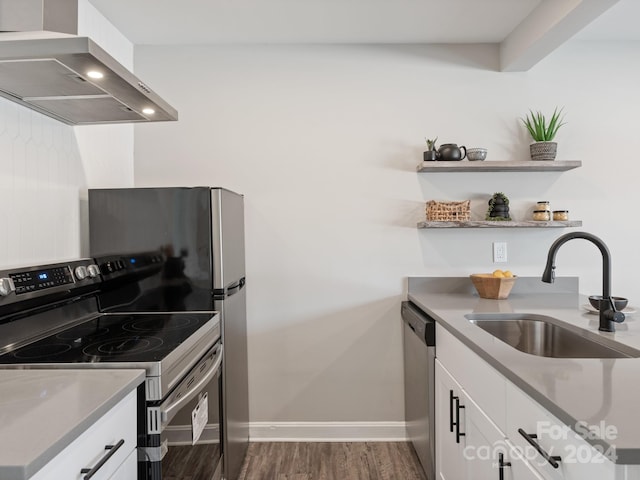 kitchen featuring white cabinetry, stainless steel appliances, dark hardwood / wood-style floors, wall chimney range hood, and sink