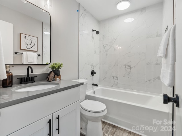 full bathroom with toilet, tiled shower / bath, hardwood / wood-style floors, and vanity