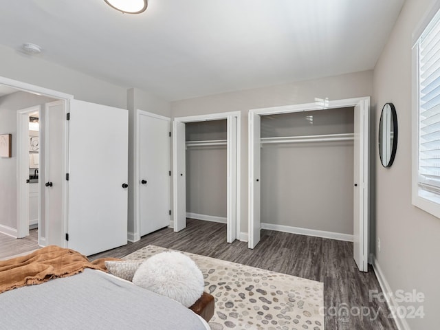 bedroom featuring two closets and dark hardwood / wood-style floors