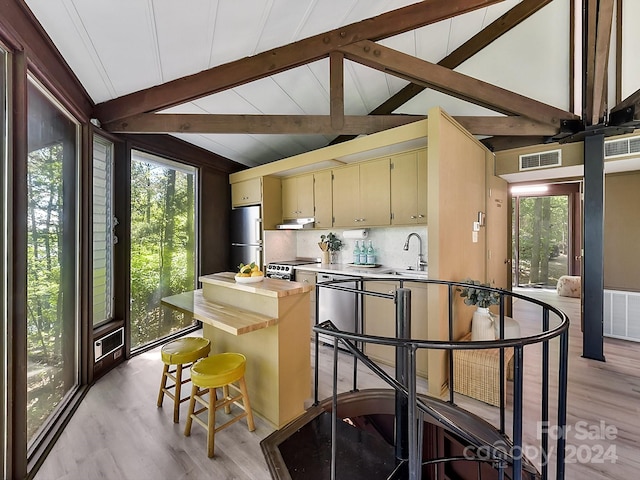 kitchen with cream cabinets, light hardwood / wood-style flooring, vaulted ceiling with beams, tasteful backsplash, and stainless steel refrigerator