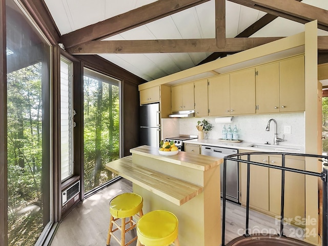 kitchen featuring light hardwood / wood-style flooring, vaulted ceiling with beams, appliances with stainless steel finishes, sink, and tasteful backsplash