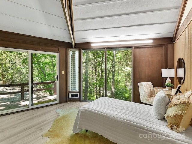 bedroom with wood walls, lofted ceiling with beams, and hardwood / wood-style floors