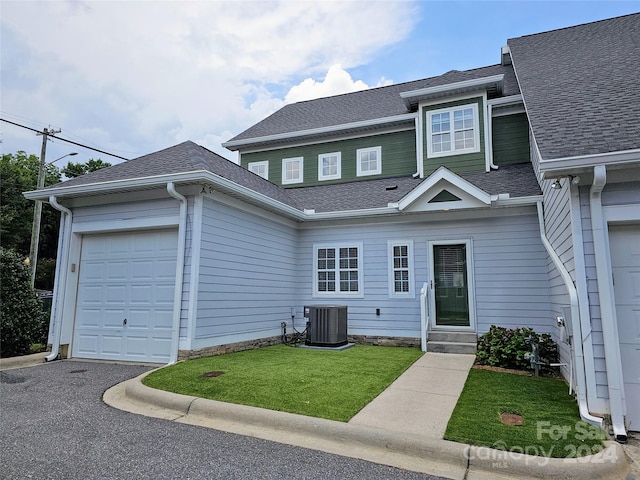 view of front of house with central AC, a garage, and a front yard