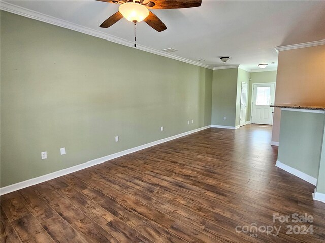 empty room featuring dark wood-type flooring, ornamental molding, and ceiling fan