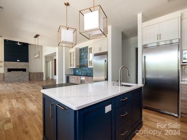 kitchen with blue cabinets, stainless steel built in refrigerator, sink, and white cabinets