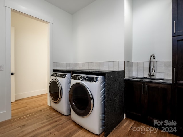 laundry area with cabinets, light hardwood / wood-style floors, sink, and washing machine and clothes dryer