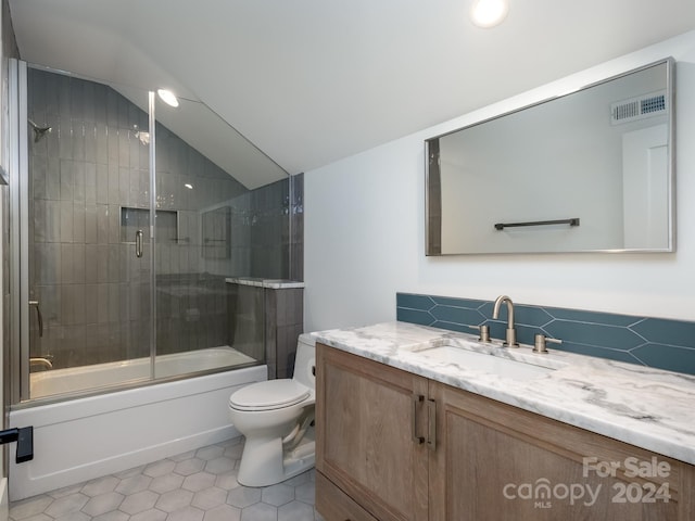 full bathroom featuring vanity, lofted ceiling, toilet, combined bath / shower with glass door, and tile patterned flooring