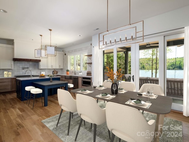 dining space featuring a water view, sink, and light hardwood / wood-style flooring