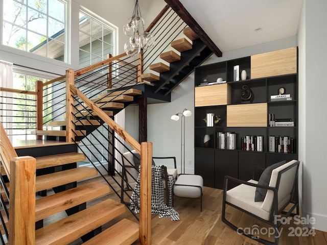 stairs with wood-type flooring and a notable chandelier