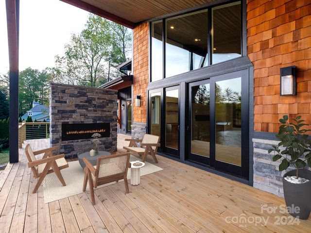 wooden deck with an outdoor stone fireplace