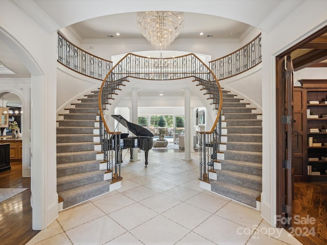 foyer entrance with light tile flooring, crown molding, and an inviting chandelier