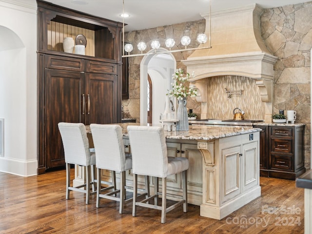 bar featuring cream cabinetry, decorative light fixtures, hardwood / wood-style floors, and light stone countertops