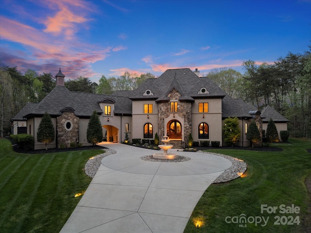 french provincial home with a lawn