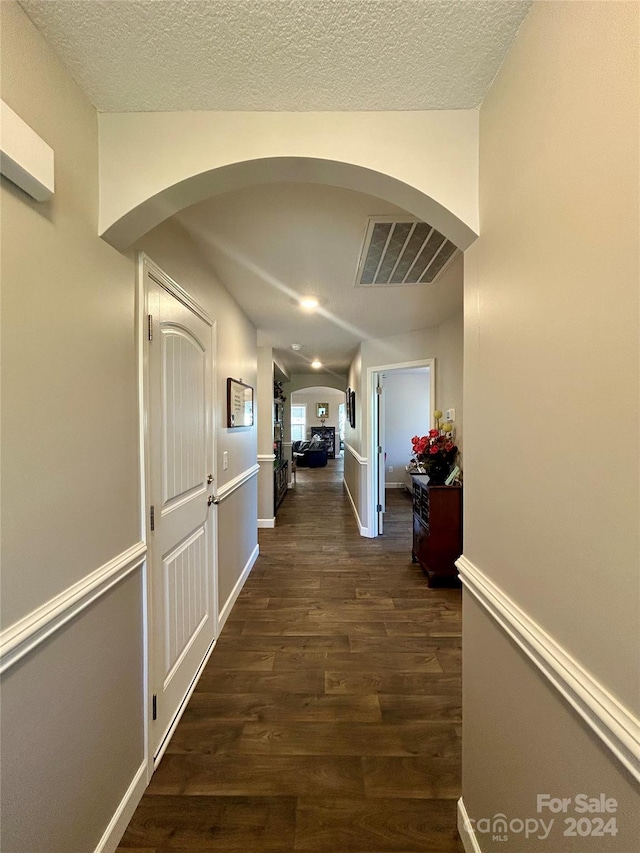 hall with dark hardwood / wood-style flooring and a textured ceiling