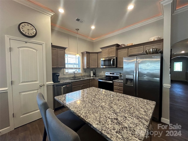 kitchen with a kitchen island, sink, decorative light fixtures, dark hardwood / wood-style flooring, and stainless steel appliances