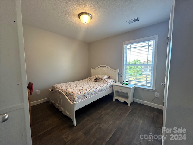 bedroom with dark hardwood / wood-style floors and a textured ceiling