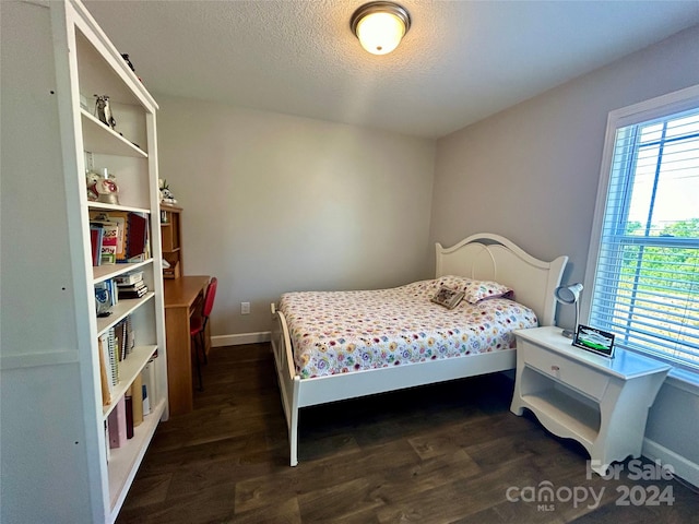 bedroom with dark hardwood / wood-style floors and a textured ceiling