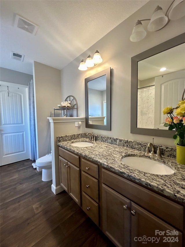 bathroom with hardwood / wood-style flooring, dual bowl vanity, and toilet