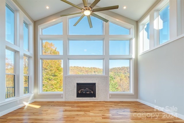 unfurnished sunroom featuring vaulted ceiling, ceiling fan, and a tiled fireplace