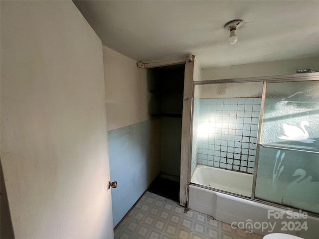 bathroom featuring tile floors, toilet, and shower / bath combination with glass door