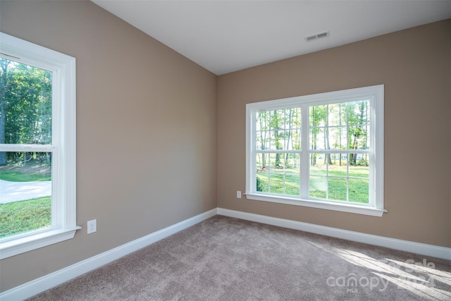 carpeted spare room featuring lofted ceiling and plenty of natural light