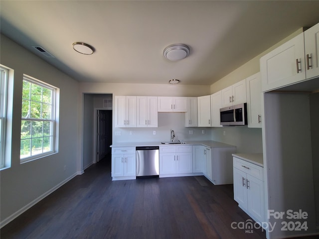 kitchen with appliances with stainless steel finishes, white cabinetry, sink, and dark wood-type flooring