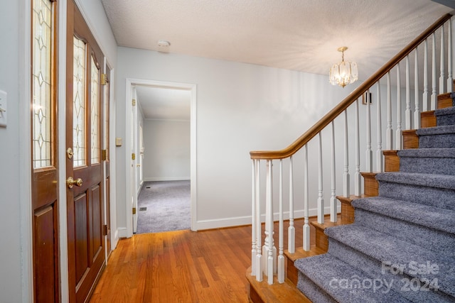 entrance foyer with a notable chandelier, carpet, and a textured ceiling