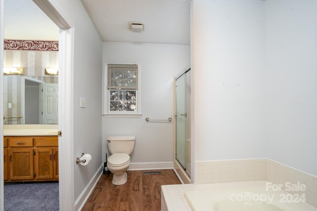 full bathroom featuring a textured ceiling, plus walk in shower, toilet, vanity, and wood-type flooring