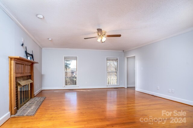 unfurnished living room featuring ceiling fan, ornamental molding, a textured ceiling, and light hardwood / wood-style floors