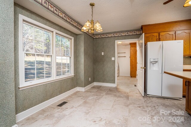 unfurnished dining area featuring a notable chandelier, a textured ceiling, and light tile patterned floors