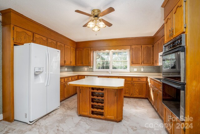 kitchen with double oven, light tile patterned flooring, white refrigerator with ice dispenser, a center island, and ceiling fan