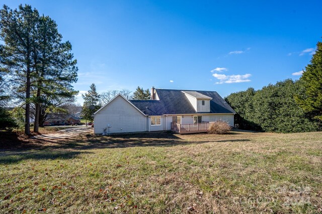 back of house featuring a lawn and a deck