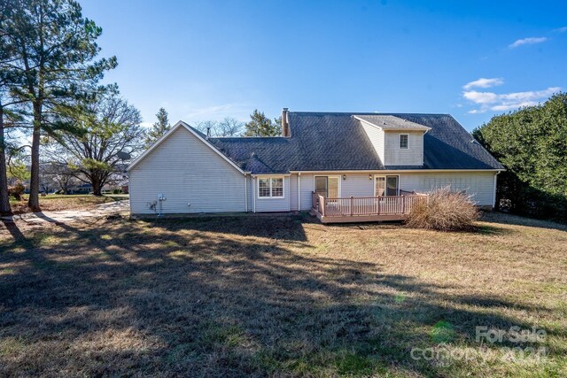 back of house featuring a lawn and a wooden deck