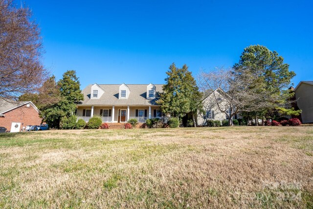 cape cod home featuring covered porch and a front yard