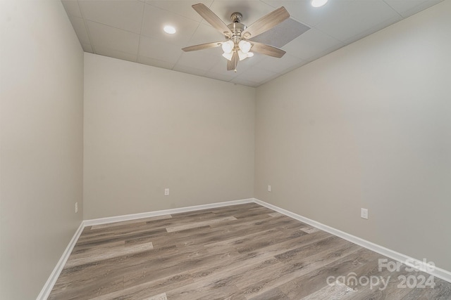 spare room with a drop ceiling, ceiling fan, and hardwood / wood-style flooring