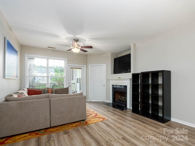 living room featuring light hardwood / wood-style flooring, ceiling fan, and a fireplace