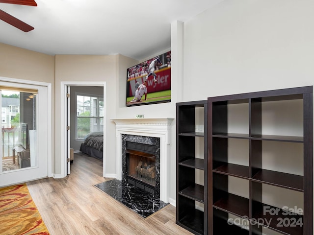 living room with ceiling fan, light wood-type flooring, and a high end fireplace