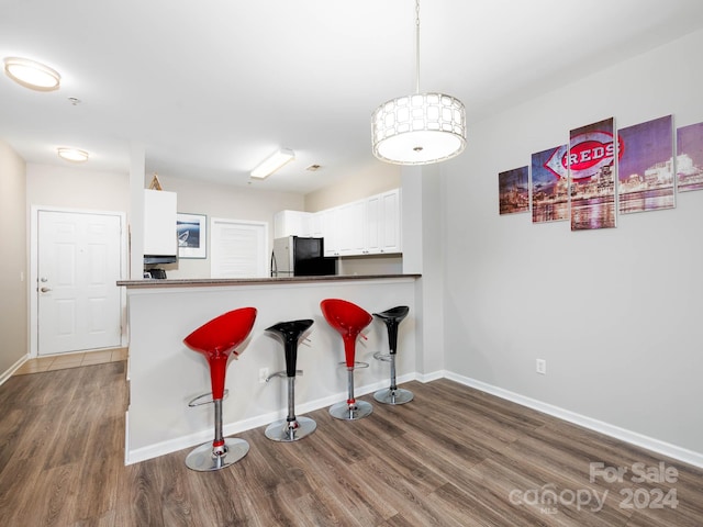 kitchen featuring kitchen peninsula, dark hardwood / wood-style flooring, stainless steel fridge, and white cabinets