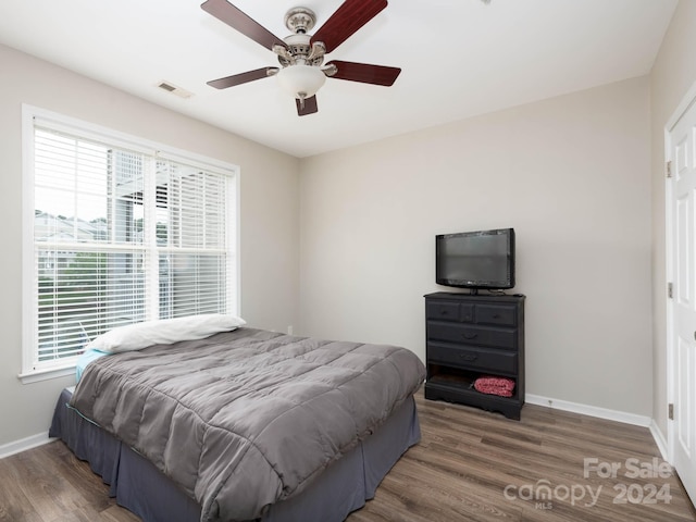 bedroom featuring hardwood / wood-style floors, ceiling fan, and multiple windows