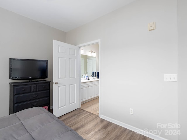 bedroom with ensuite bath and light hardwood / wood-style flooring