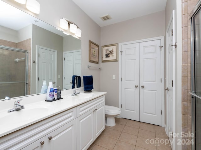 bathroom with walk in shower, toilet, tile flooring, and double sink vanity