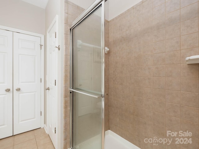 bathroom with a shower with shower door and tile flooring