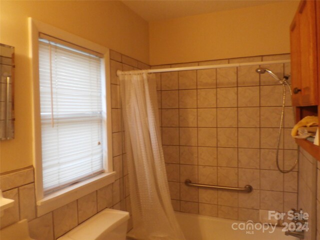 bathroom with shower / tub combo, tile walls, and toilet