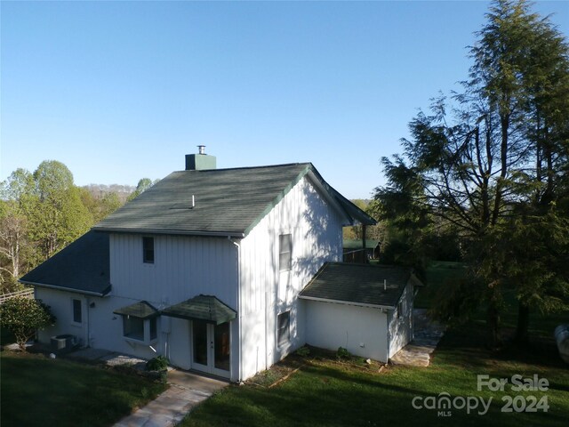 view of property exterior with french doors, a yard, and central air condition unit