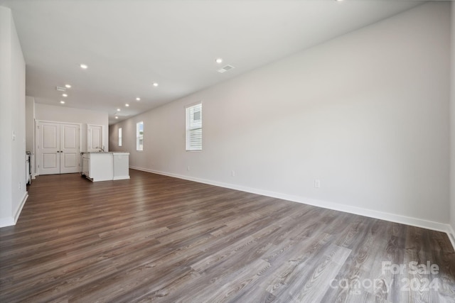 unfurnished living room featuring wood-type flooring and sink