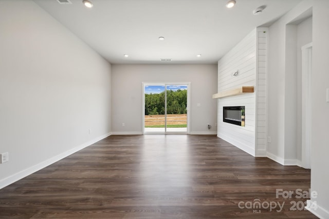 unfurnished living room featuring a fireplace and dark wood-type flooring